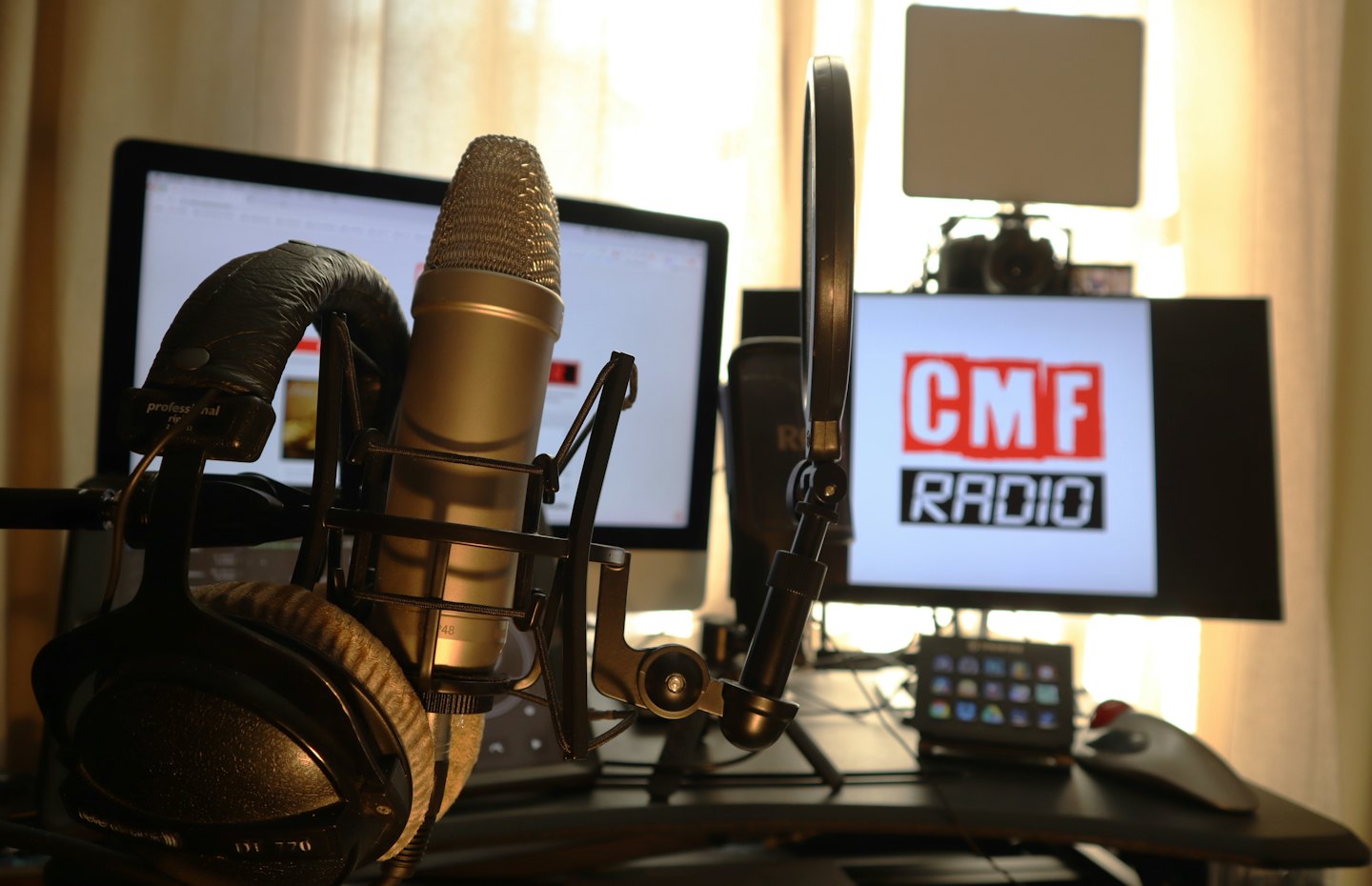 Podcastmikrofon mit Popschutz und Kopfhörern auf einem Schreibtisch.